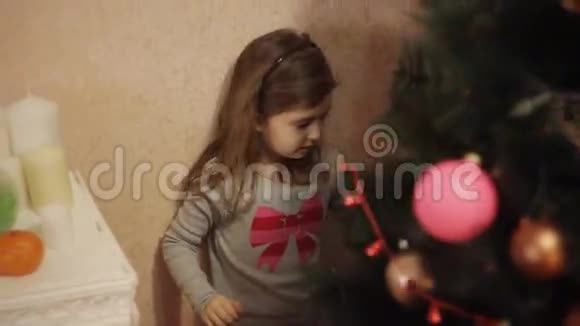 两个微笑的小女孩在家里的新年树上装饰圣诞装饰品圣诞树用冷杉锥新视频的预览图