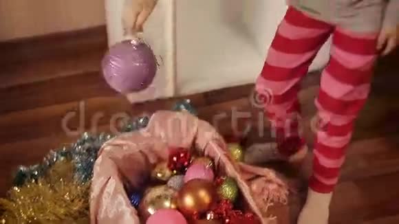 两个微笑的小女孩在家中的新年树上装饰圣诞装饰品视频的预览图