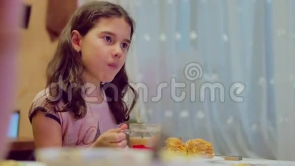 少女喝茶吃蛋糕室内生活方式早餐时看电视视频的预览图