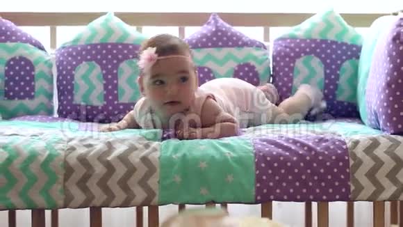 美丽快乐的小女孩趴在婴儿床上笑视频的预览图
