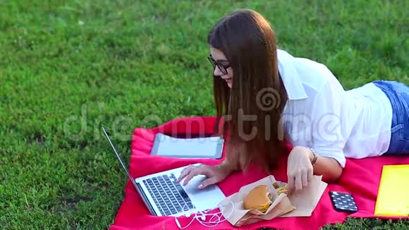 年轻女性按下键盘在绿草上吃薯条视频的预览图