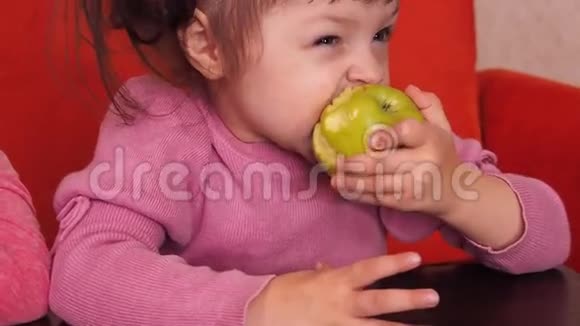 孩子们吃苹果两个姐妹坐在橙色的沙发上吃黄色的苹果视频的预览图