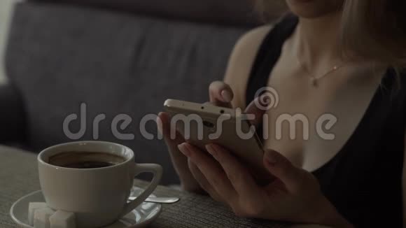 在咖啡馆的餐桌上背景咖啡杯上使用手机的年轻女子视频的预览图