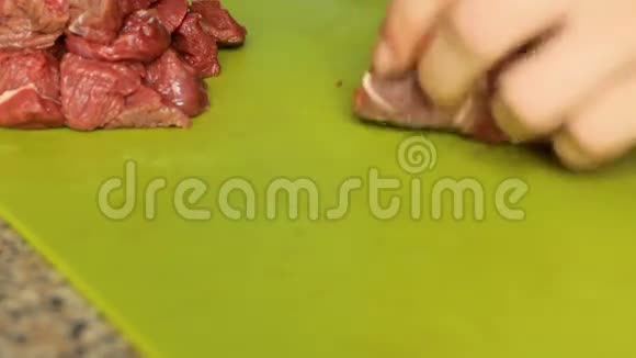 女性的手在切割板特写上切生肉在厨房准备晚餐视频的预览图