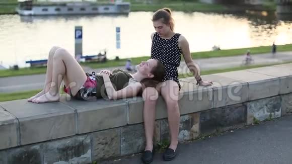 两个朋友十几岁的女孩坐在城市长廊上亲密交谈视频的预览图