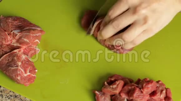 女性的手在切割板特写上切生肉在厨房准备晚餐视频的预览图