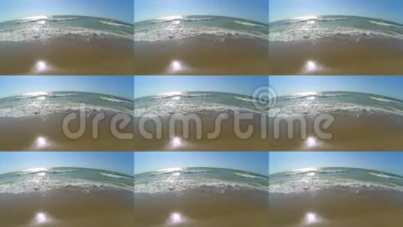 海浪与白色泡沫卷到沙滩晴朗温暖的夏日视频的预览图