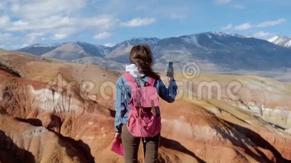 漂亮的女孩穿着牛仔裤夹克在电话里拍了20s4k的山的照片视频的预览图