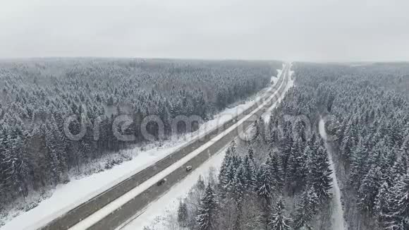4K道路在冬季森林与驾驶汽车在降雪空中全景消失的角度视频的预览图