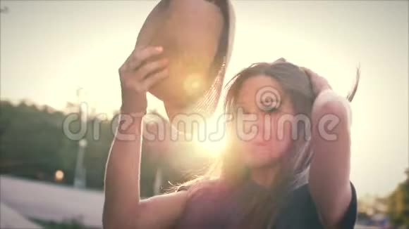 快乐美丽的女人用双手在夕阳下做心形女孩用橙色的太阳耀斑举起爱的象征姿态视频的预览图
