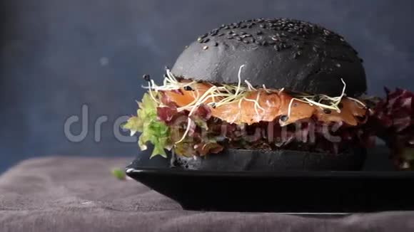 两个自制的黑色汉堡里面有咸鲑鱼甜菜根芽菜和黑盘上的绿色沙拉视频的预览图