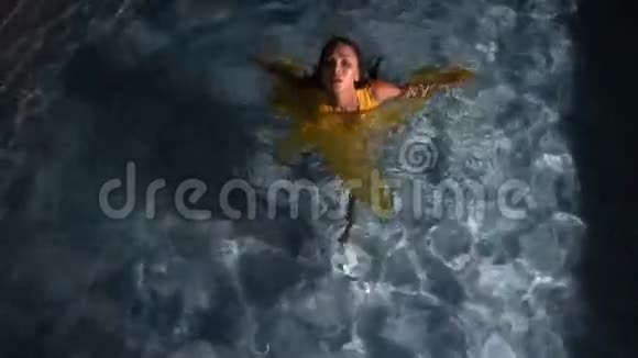 在游泳池里穿着黄色连衣裙的美丽黑发女人视频的预览图