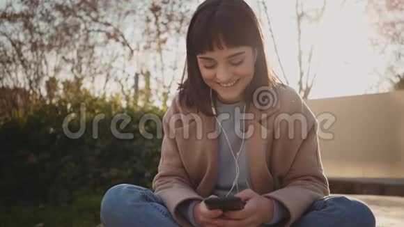 漂亮的女人在公园里使用智能手机视频的预览图