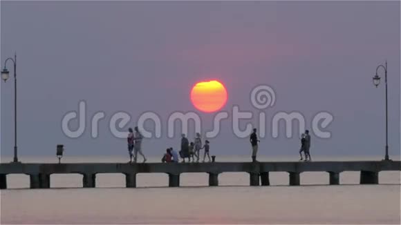 日落时分码头上的渡轮与人们一起航行视频的预览图