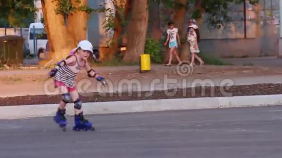 穿着柏油路溜冰鞋帽的小女孩视频的预览图