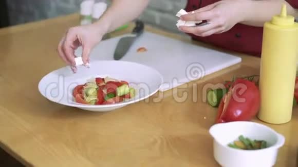 女人切奶酪做蔬菜沙拉在餐厅厨房做4k视频的预览图