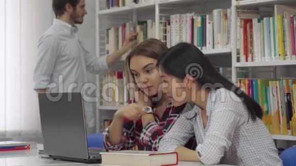 两个女孩在图书馆用笔记本电脑学习视频的预览图