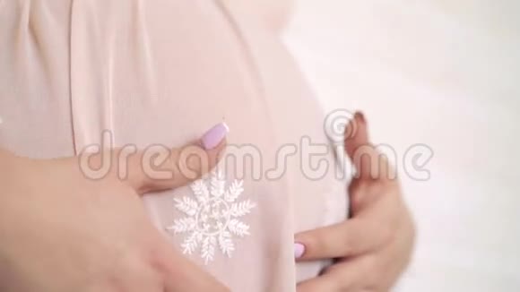 接近孕妇抚摸大肚子在夜光白色背景4K视频的预览图