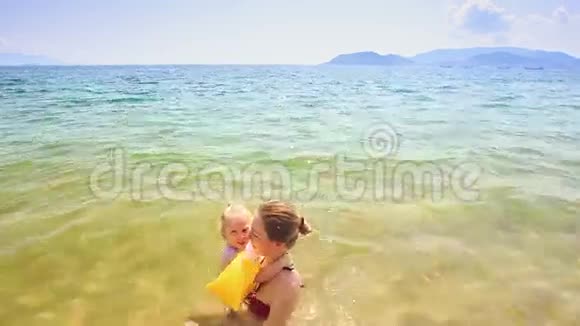 金发母亲挽着小女儿在蔚蓝的大海里视频的预览图