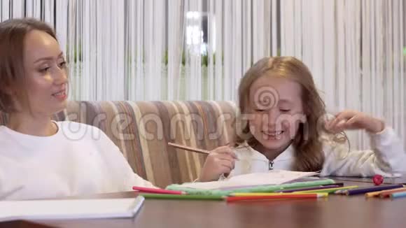 一个美丽的小女孩和她妈妈一起画画的侧视图视频的预览图