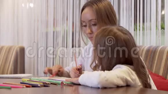 一个美丽的小女孩和她妈妈一起画画的侧视图视频的预览图