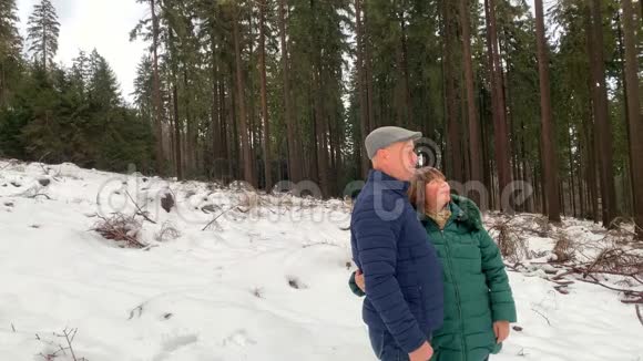 穿着夹克的女人和男人在冬天穿过一片雪林视频的预览图