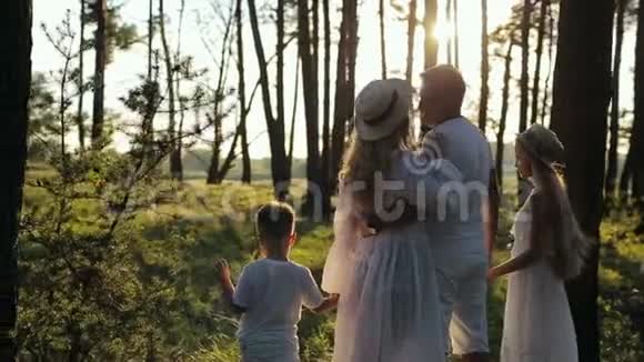四口之家在森林里玩得开心穿着白色衣服和草帽的父母和孩子都很高兴视频的预览图