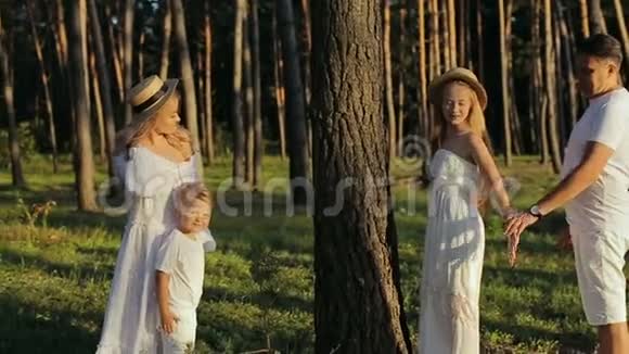 四口之家在森林里玩得开心穿着白色衣服和草帽的父母和孩子都很高兴视频的预览图