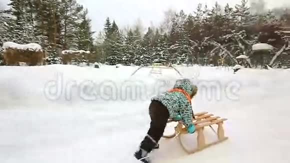笑的男孩跑着推着他的雪橇视频的预览图