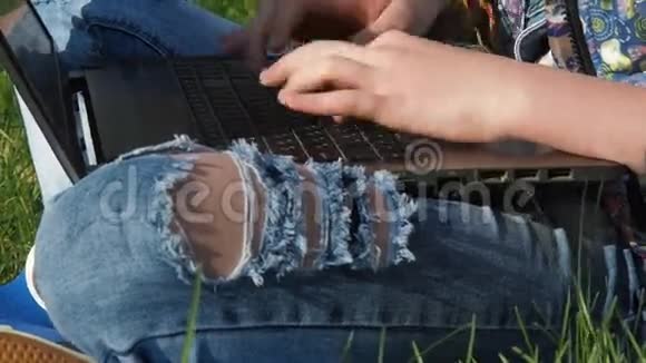 牛仔裤和笔记本电脑戴手镯的青少年的手印在笔记本电脑上破旧的牛仔裤视频的预览图