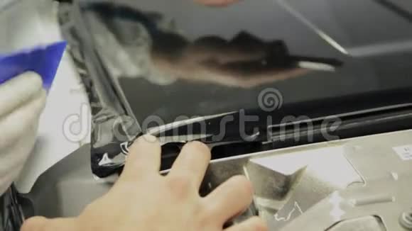 近距离拍摄男子切割乙烯基膜同时调整汽车视频的预览图