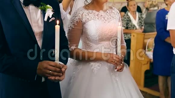 婚礼期间新郎和新娘手里拿着厚厚的白蜡烛视频的预览图