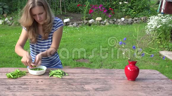 村民金发女孩豆荚绿色健康豌豆在木桌上4K视频的预览图