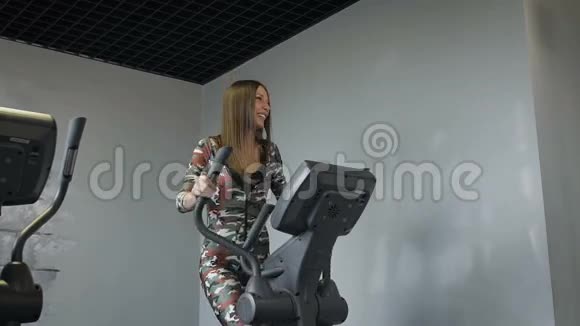漂亮的年轻女士在健身房里用椭圆机训练心情很好视频的预览图