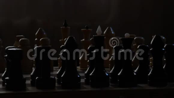 棋盘与棋子在黑暗中黑色背景旋转镜头国际象棋戏剧战视频的预览图