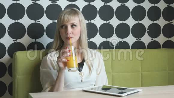 漂亮的模特在咖啡馆喝橙汁视频的预览图
