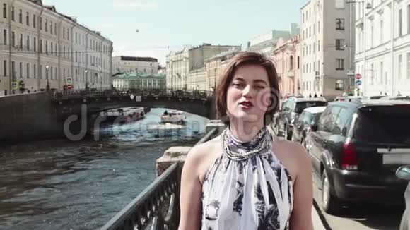 穿着斑点裙子的快乐女孩沿着老城区的河流歌唱视频的预览图