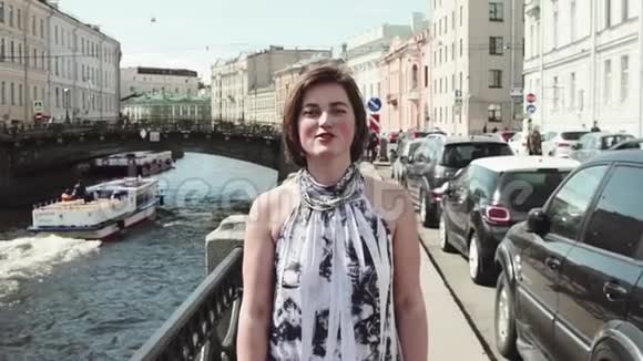 穿着斑点裙子的年轻女子沿着老市中心的河流唱歌视频的预览图