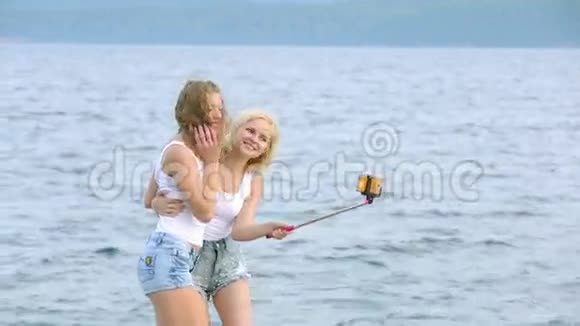 两个朋友女人用手机在河边自拍两个小女孩在河边玩耍自拍视频的预览图