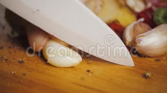 用刀智利和胡椒将大蒜切在木切割板上视频的预览图