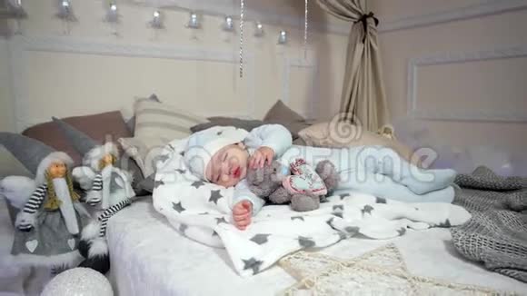 可爱的小男孩小孩子睡觉婴儿躺在床上的滑块和帽子甜蜜的梦可爱的男孩视频的预览图