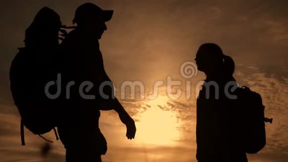 夕阳下幸福的家庭游客剪影拥抱亲吻团队旅游理念背着背包的男女情侣视频的预览图