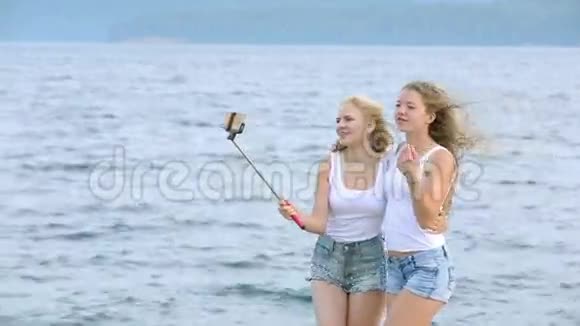 两个朋友女人用手机在河边自拍两个小女孩在河边玩耍自拍视频的预览图