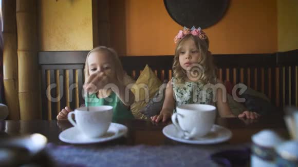 两个可爱的小女孩在咖啡馆里喝茶视频的预览图
