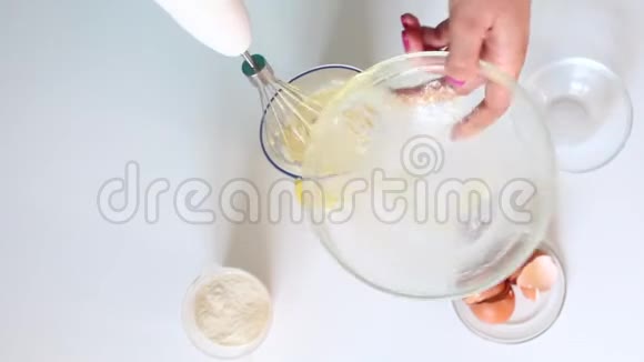 一个女人正在准备面团把搅拌机和鸡蛋糖混合加入面粉视频的预览图