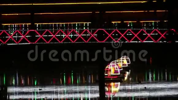东南亚夜间横跨河流的霓虹灯行人天桥的中长焦视图视频的预览图