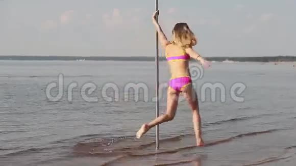 美丽的女孩在沙滩上的杆子上跳舞视频的预览图