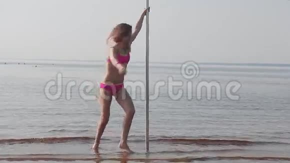 美丽的女孩在沙滩上的杆子上跳舞视频的预览图