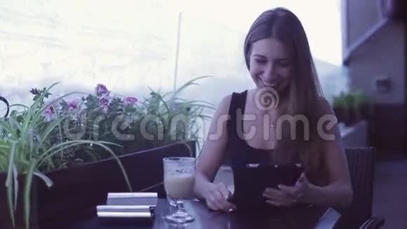 坐在咖啡馆里用笔记本电脑的年轻美女视频的预览图