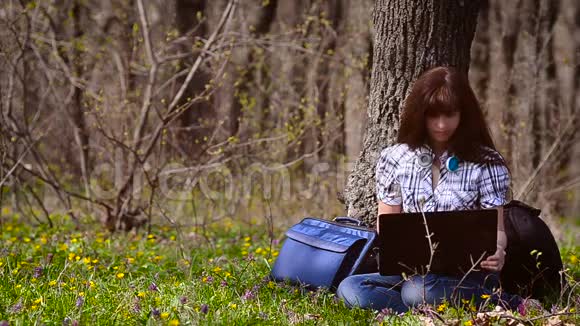 一个女人在森林里的电脑前工作视频的预览图